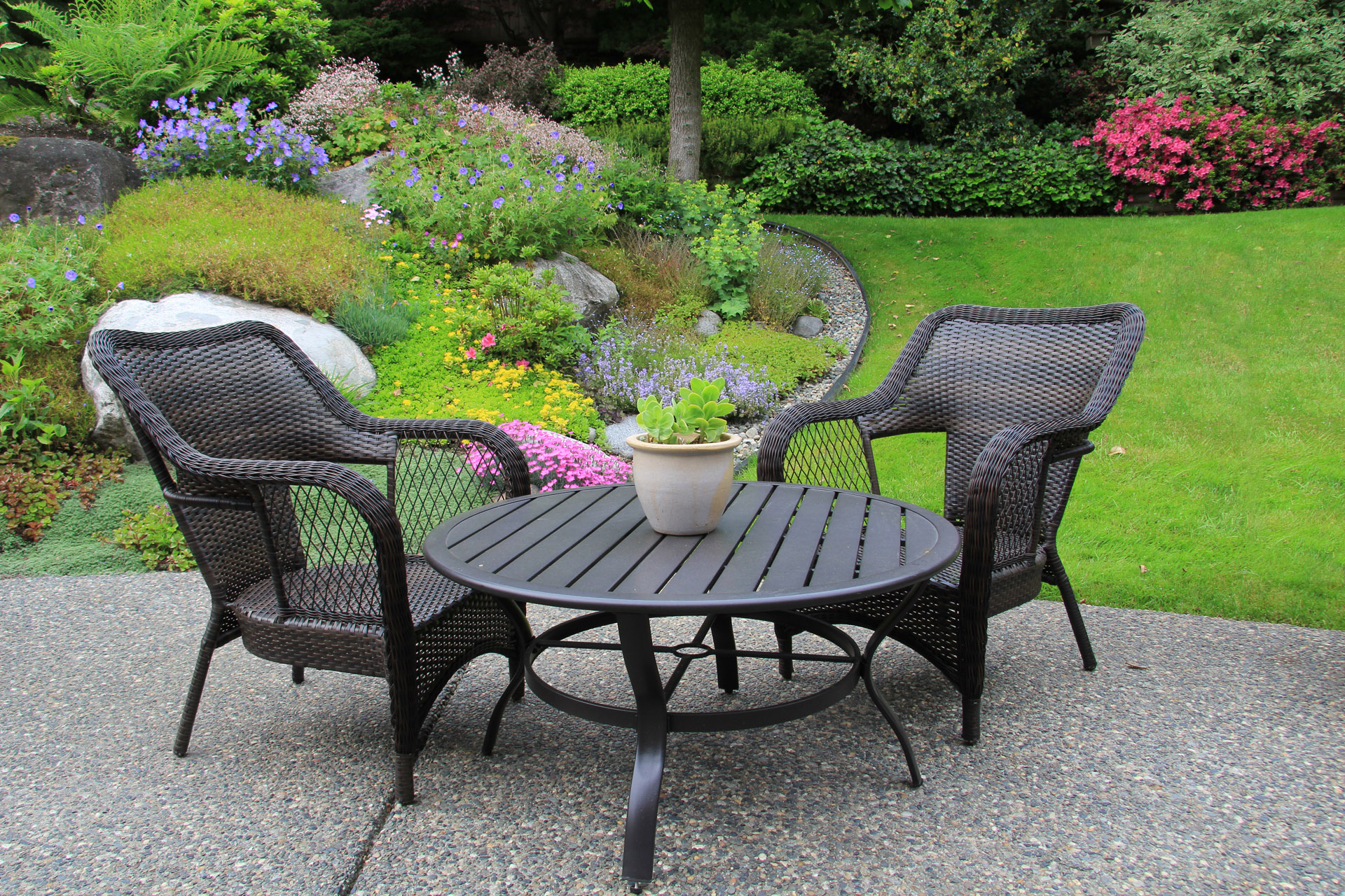 zwei geflochtene Sitzmöbel am Tisch im Garten